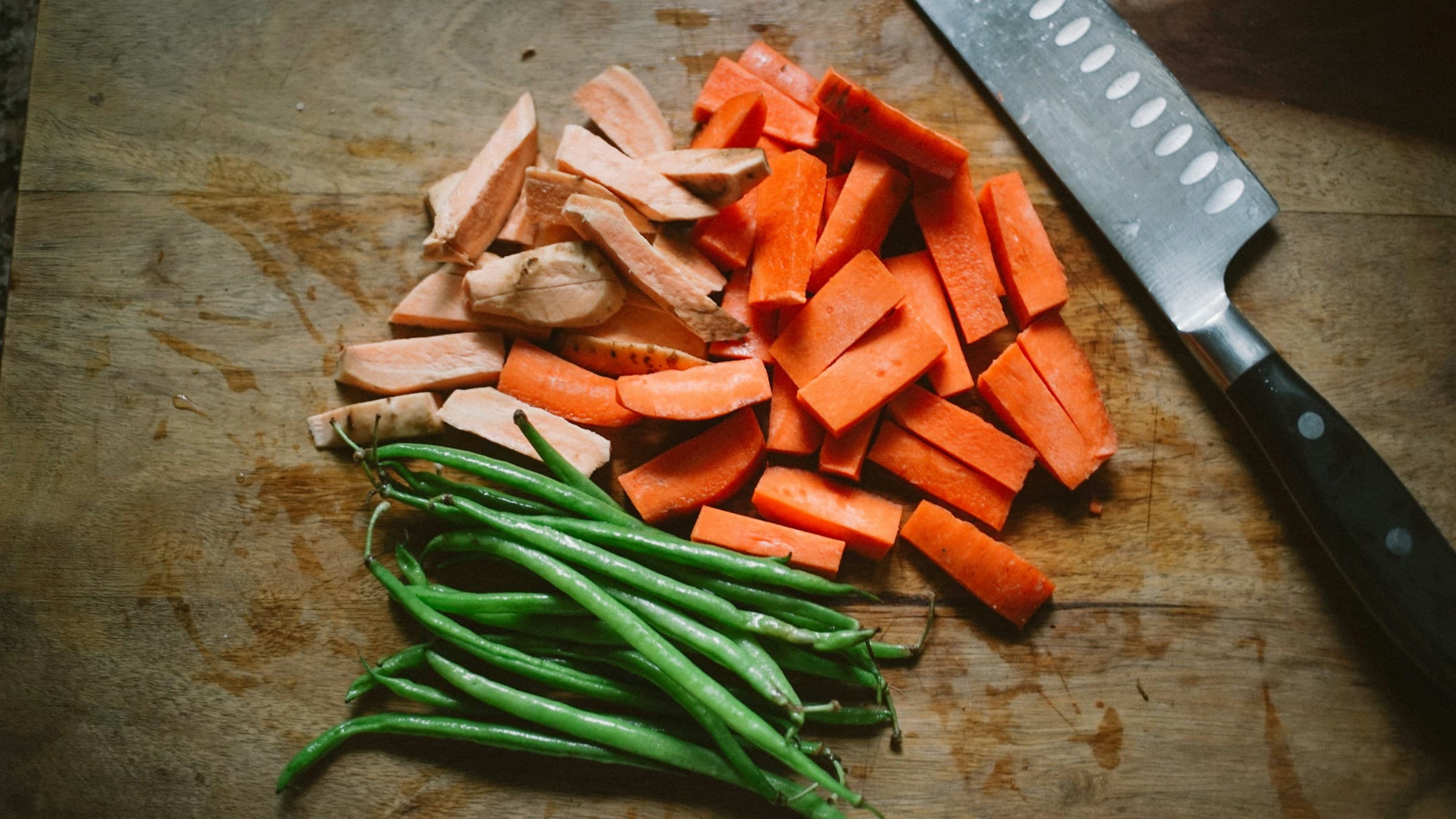 Chopped carrots and green beans on a wooden board